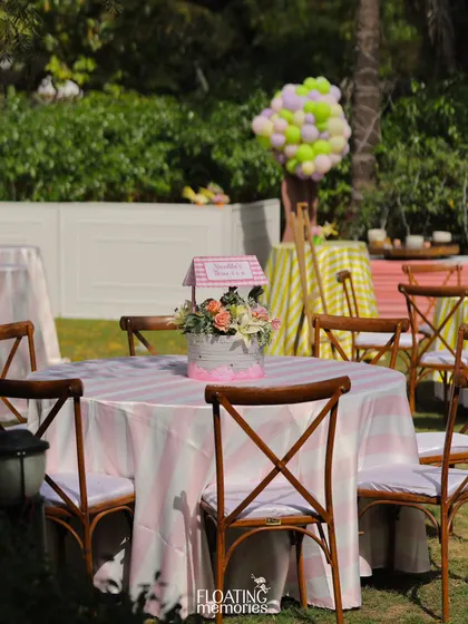 The guest seating was designed to match the theme, with pink and white striped tablecloths and charming floral centerpieces. The cross-back chairs add a rustic yet elegant touch to the outdoor birthday party setup.