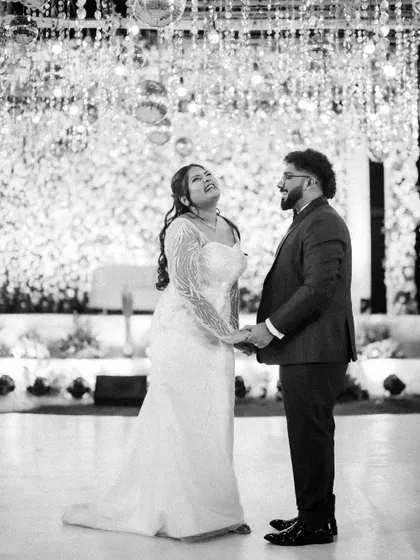A joyful black and white portrait of the couple under a canopy of sparkling lights. Their laughter and connection are the focus of this beautiful, candid moment.