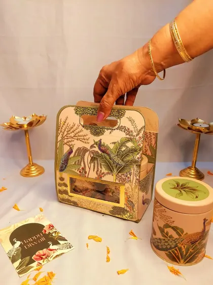 Our peacock theme is a festive favorite. This hamper, housed in a beautiful printed box, includes three matching tins filled with dry fruits, chocolates, and cookies.