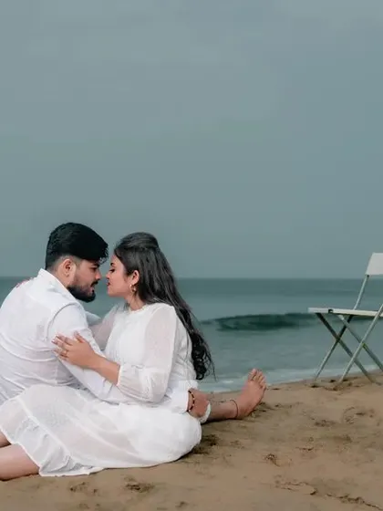 An intimate moment on a quiet beach, with the couple sitting on the sand. The two empty chairs suggest a story of a world that is just for them.