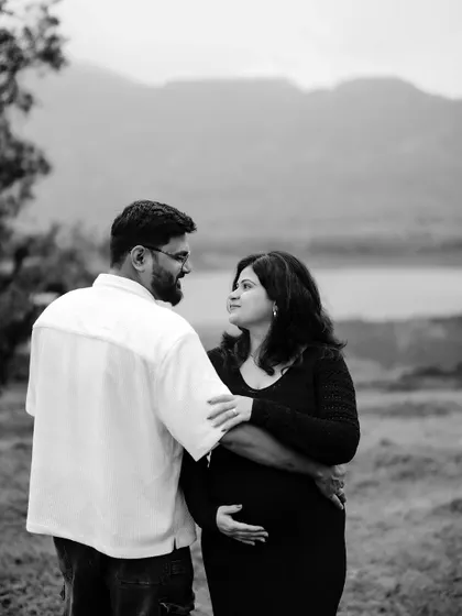 A quiet, intimate black and white portrait of the couple by the lake. They share a gentle look, their embrace full of unspoken love.