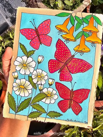 Holding the butterfly and flower painting in my garden. The natural sunlight makes the colors of the acrylic paint look bright and cheerful.