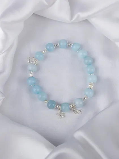 A light blue beaded bracelet with silver moon and star charms.