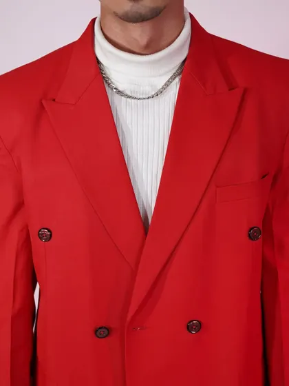 A close-up of the bold red suit jacket. The double-breasted design and sharp lapels give it a modern, high-fashion feel.