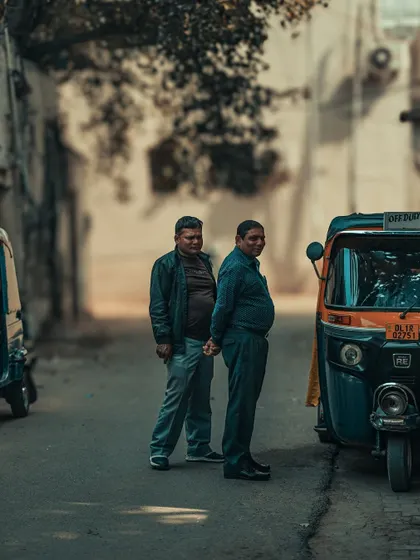 Two auto-rickshaw drivers chatting in a quiet lane. These candid interactions offer a small window into the daily lives of the people who keep the city moving.