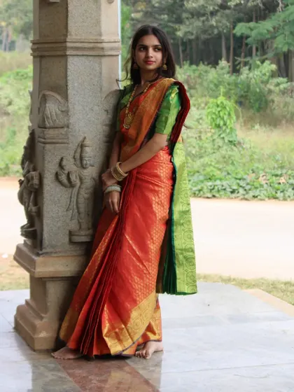A full view of an elegant temple-side photoshoot. The rich orange and green silk saree was pre-pleated by me to ensure a perfect drape throughout the day.