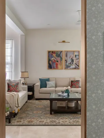 A view from the foyer into the 'House of Kismish' living room, where subtle wallpaper and a wooden door frame create a warm, welcoming entrance to the main living area.