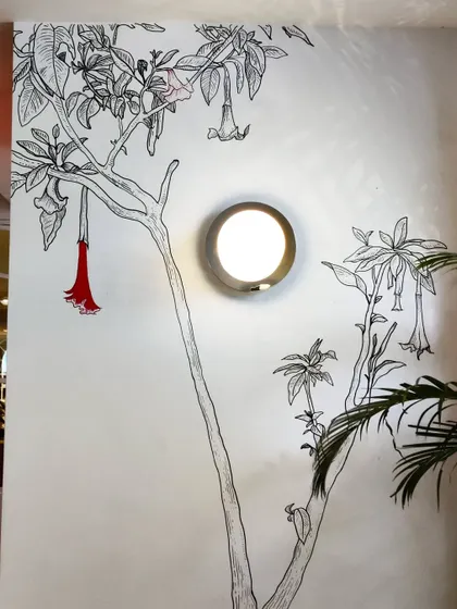 The Angel's Trumpet flower doodle, with a single pop of red color, creates a striking detail on the wall.