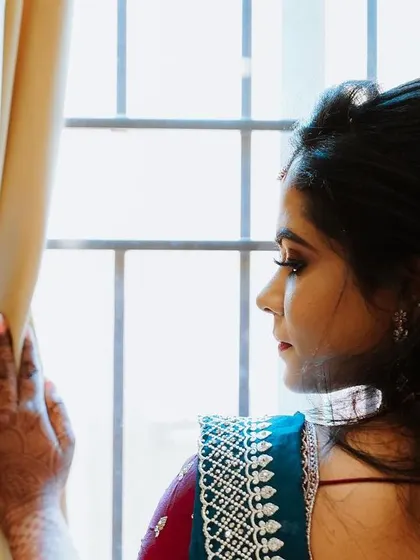 A pensive portrait of the bride looking out a window, the natural light creating a soft and thoughtful mood.