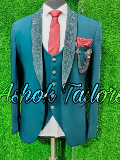 A teal green three-piece suit with an embellished lapel and a red tie for a pop of contrast.