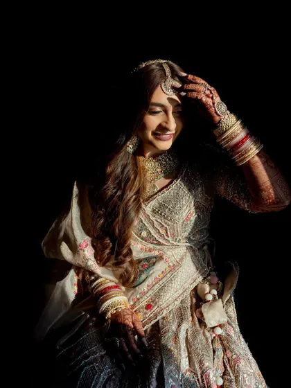 A beautiful bridal portrait of Yashavi, with dramatic lighting that highlights her smile and the intricate details of her outfit.