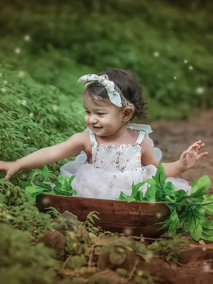 A candid moment of a toddler interacting with her natural surroundings, with a touch of sparkle added to enhance the magical, forest-fairy feel.