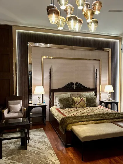 A closer view of the bedroom's headboard wall, which features a layered design of fabric, ribbed panels, and mirrors with brass-finished trim. The intricate details and mix of materials create a sense of depth and timeless elegance.