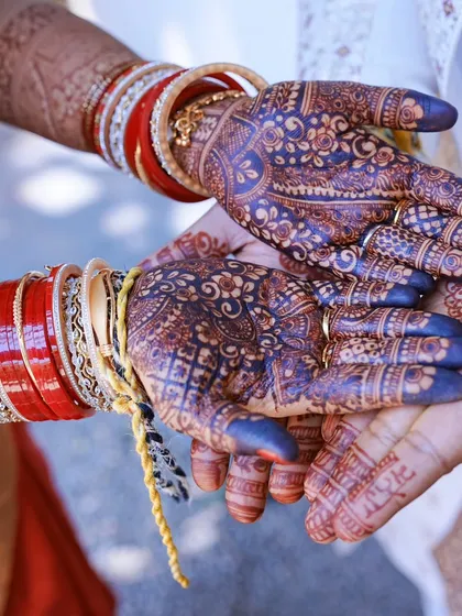The fully matured, deep maroon stain is just breathtaking. Here you can see the henna on a bride's hands during a ceremony, beautifully complementing her red bangles.