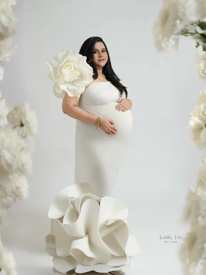 Framed by flowers. This creative composition uses large paper flowers to frame the mother in her sculptural gown, enhancing the theme of blooming and new life.