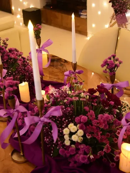 The tablescape for the purple party, featuring a rich purple runner, floral arrangements, and a mix of tall and short candles to create a layered, romantic glow.