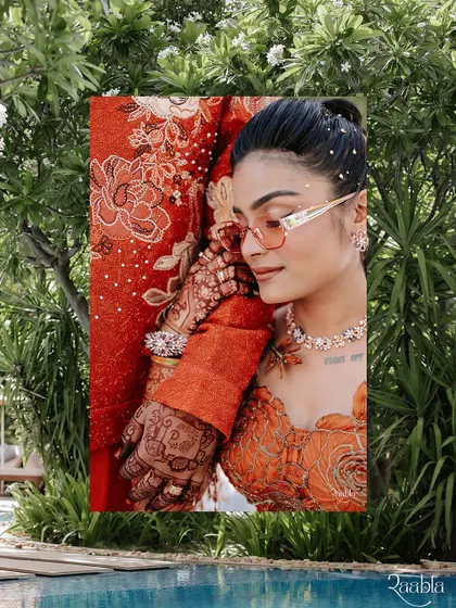A stylish, editorial-style shot of the bride at the Carnival-themed event, her vibrant orange outfit perfectly complementing the poolside setting.