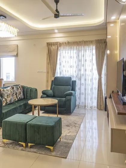 This shot highlights the flow between the living and dining areas, unified by a consistent false ceiling design and lighting scheme. The emerald green sofa acts as a beautiful focal point.