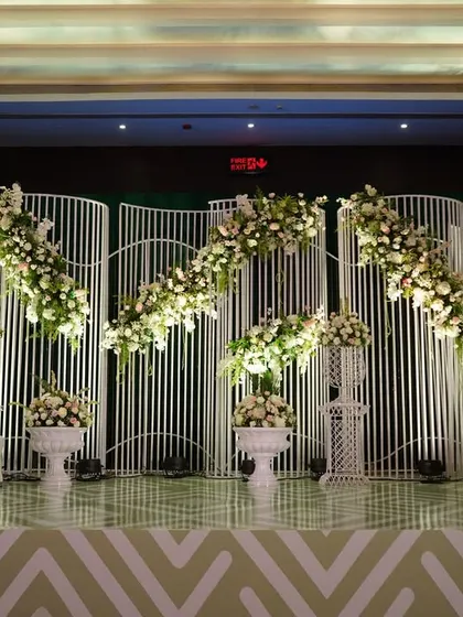 Modern elegance is about clean lines and impactful design. This reception stage features a unique, wave-like white backdrop adorned with delicate floral arrangements, creating a look that is both minimalist and incredibly chic.