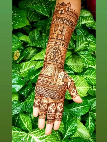 A stunning bridal design against a lush green background. The artwork features palace architecture and peacock motifs, extending up the arm for a truly grand statement.
