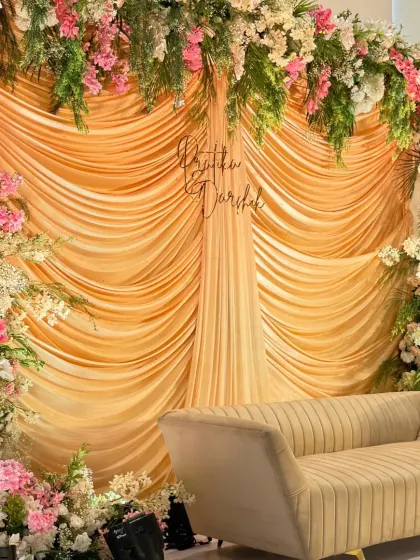 A closer look at our pastel and gold stage. The richly draped golden fabric is perfectly complemented by the overflowing arrangements of pink, peach, and white flowers, with a custom hashtag sign nestled in the center.