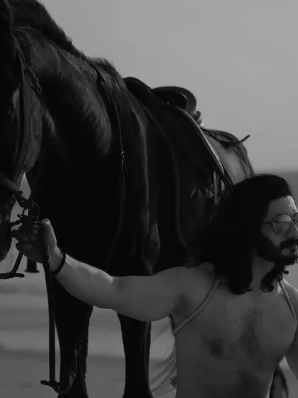 A series of black and white images from a male editorial shoot on the beach with a horse. The monochrome style gives these photos a classic, timeless, and heroic quality.