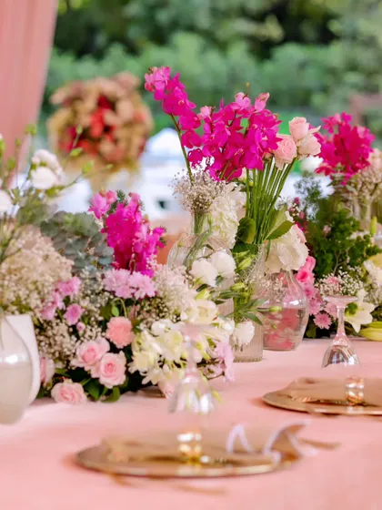 The long dining table is adorned with a continuous line of fresh flowers in different vases, creating a beautiful, garden-like tablescape.