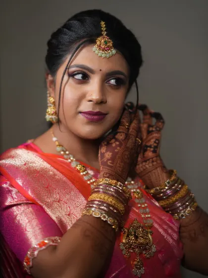A beautiful bride, Ruchitha, getting ready for her ceremony. Her deep mehendi stain perfectly complements her traditional jewelry and attire.