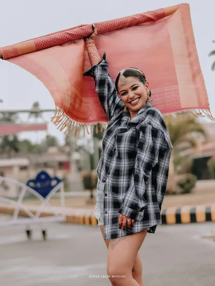 A fun, modern twist on a traditional moment, with the bride Arya holding up a piece of her saree. This shows her playful personality shining through.