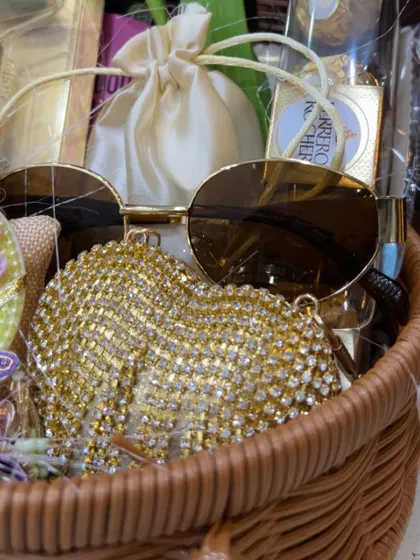 A peek inside the sister's Rakhi hamper, showing the trendy sunglasses and a glittering gold clutch purse.
