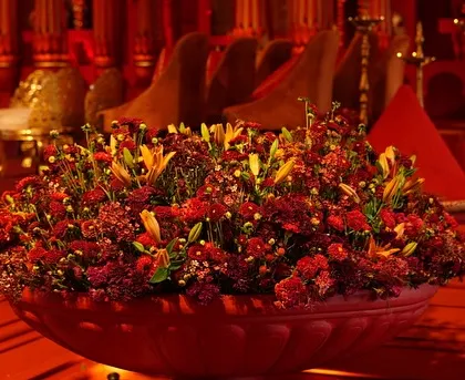 A large urn filled with a lush arrangement of red and yellow flowers, a key decor element in the 'Lal Bagh' wedding.