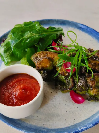 Grilled broccoli tapas served with a side of greens and a spicy tomato dip.