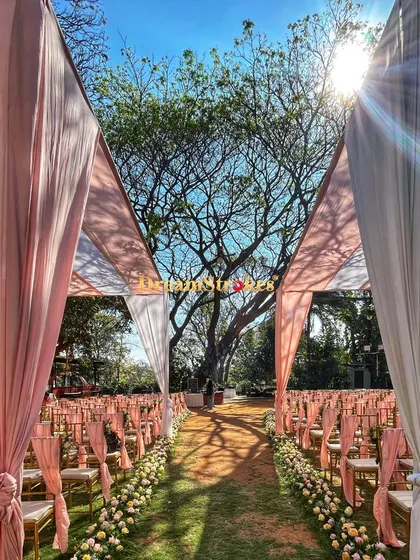 The sunlight filtering through the trees and drapes adds a magical quality to this morning wedding ceremony setup.