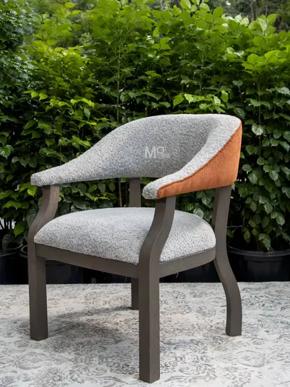 The Versa Armchair, a seamless blend of comfort and modern design. We used a soft, textured bouclé for the seat and a rich burnt orange accent on the outer back, set against a solid ash wood frame with a unique zig-zag leg design.