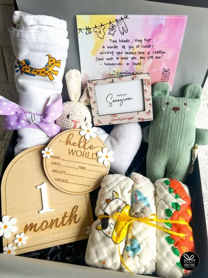 A bundle of love for a newborn. This hamper is packed with milestone cards, soft toys, a sonogram frame, and a personalized 'Hello World' plaque to record birth details.