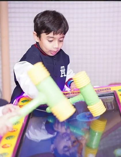 Friends work together on the hammer arcade game, a fun and interactive challenge.