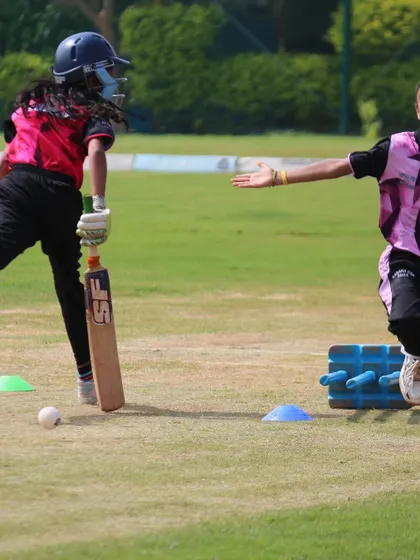 A fielding drill in progress, with players practicing quick ground fielding and accurate throws to the stumps.