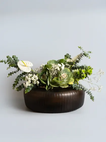 The same wide-mouthed vase, styled with a lush arrangement of green and white florals. Its low, generous shape makes it an ideal vessel for creating a stunning centerpiece for your dining table.