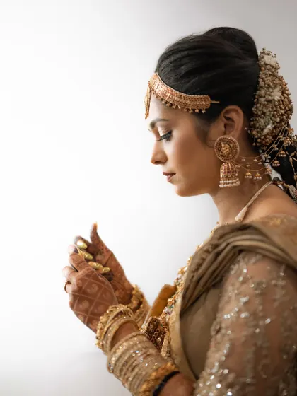 A detailed side profile of a South Indian bride. The focus is on her intricate hair adornments, jewelry, and the quiet moments of getting ready.
