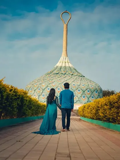 Walking towards a unique, peacock-feather-inspired monument. We seek out interesting locations for pre-wedding shoots that tell a grander story.