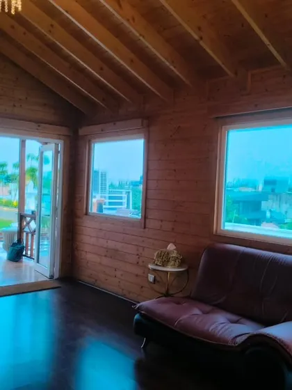 A view from inside the wooden cottage, with the door open to the landscaped terrace, showing the seamless indoor-outdoor connection.