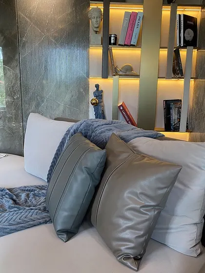 A close-up of our custom leather cushions against an artfully designed, illuminated bookshelf. Even the smallest details are considered to complement the larger wall treatments and furniture.