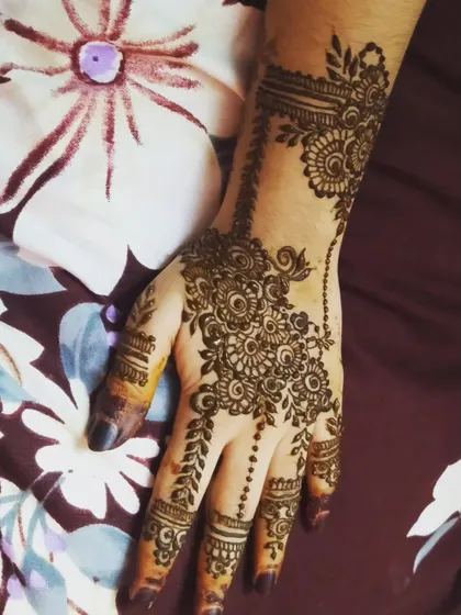 A beautiful floral and vine design on a single hand. The pattern starts at the wrist and flows down to the fingers, connected by a delicate, beaded chain motif.