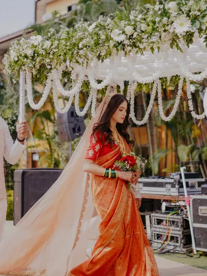 A side profile of the bride during her entrance. The sheer dupatta with a delicate border adds a touch of modern elegance to her traditional look.