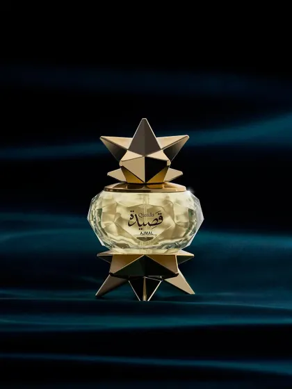 This Ajmal perfume bottle looks like a star from another galaxy. I placed it against a deep, velvety blue fabric and used soft, focused light to highlight its intricate, geometric gold structure and the faceted glass.