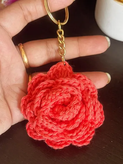 Holding a single coral-colored rose keychain. The texture is so lovely and it’s the perfect size for your keys.