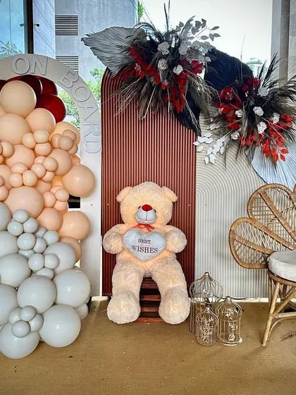A complete view of one of the photo corners from the boho-themed event. The setup includes a large teddy bear, a stylish rattan chair, and balloon arrangements against custom-made backdrops.