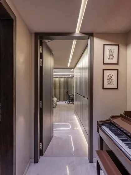 A bold red artwork and a classic piano create a striking cultural corner in this home. This passage connects different zones while serving as an artistic statement in itself.