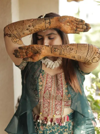 A creative pose by the bride, showcasing her full-arm mehendi designs.
