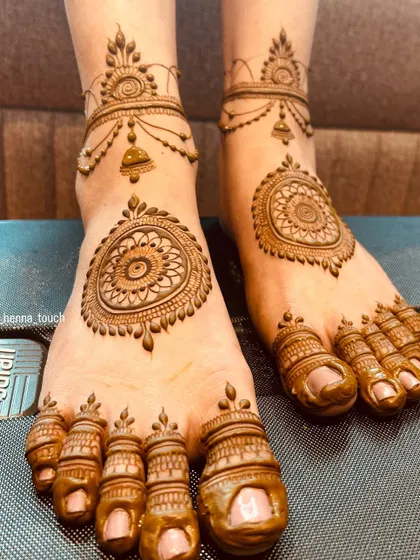 An elegant foot design that resembles traditional Indian jewelry. It features a central mandala on the foot and a delicate anklet pattern, with detailed work on the toes.